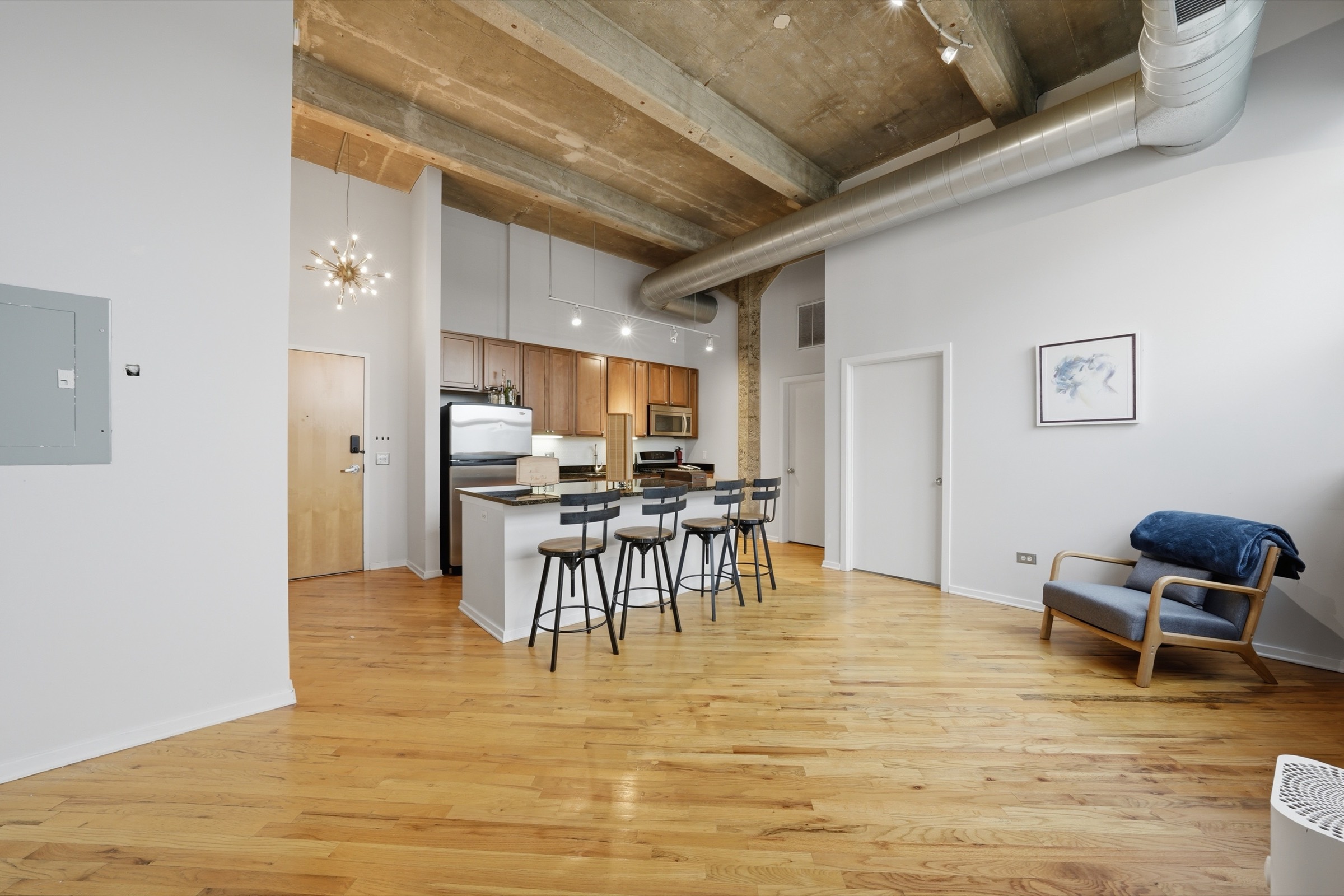 The main room looking toward the kitchen, with concrete ceilings and hardwood floors