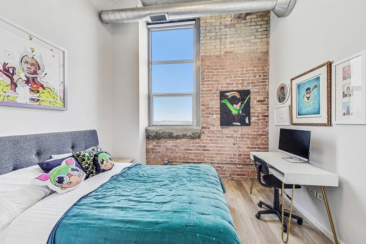 Bedroom two with desk corner, brick wall, and tall window